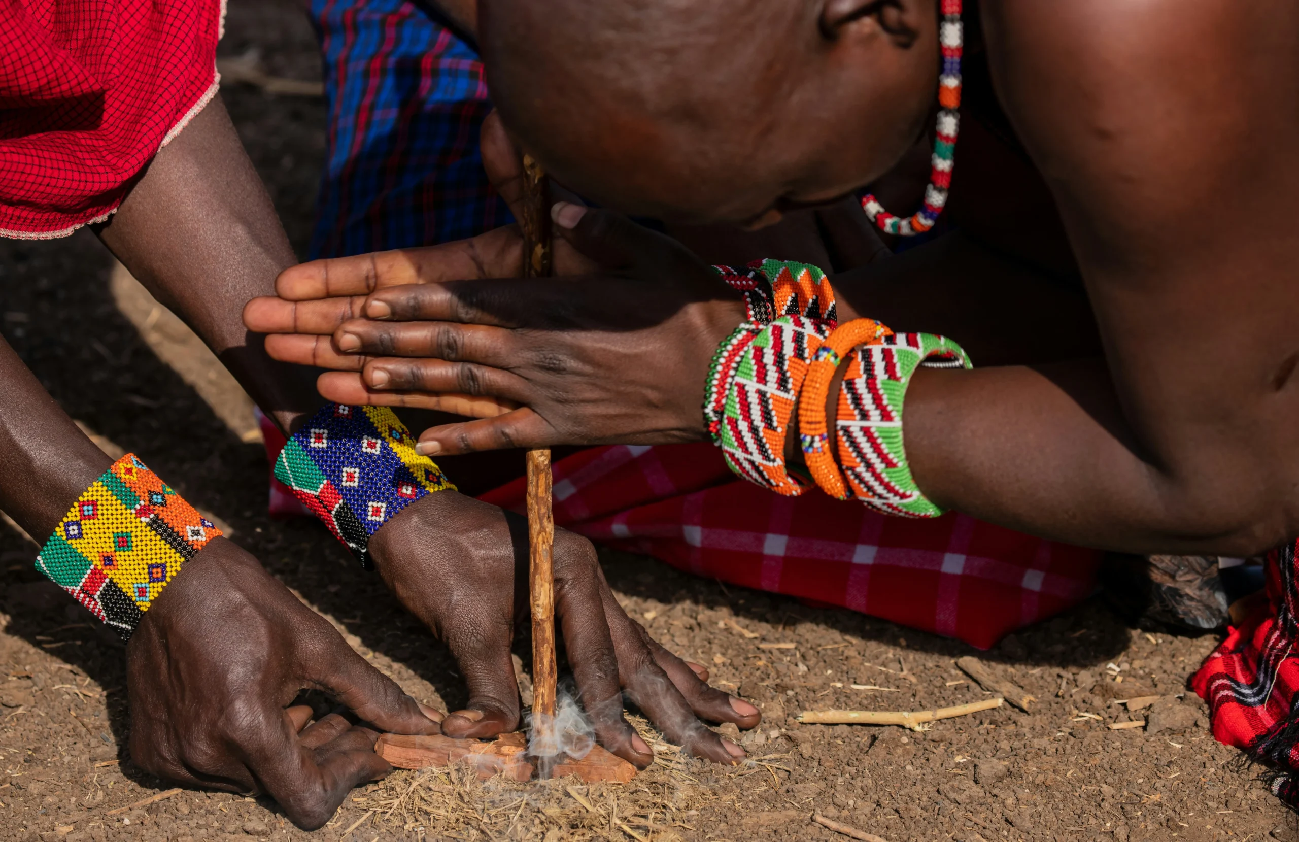 the maasai lighting a fire with sticks on a maasai village visit in masai mara