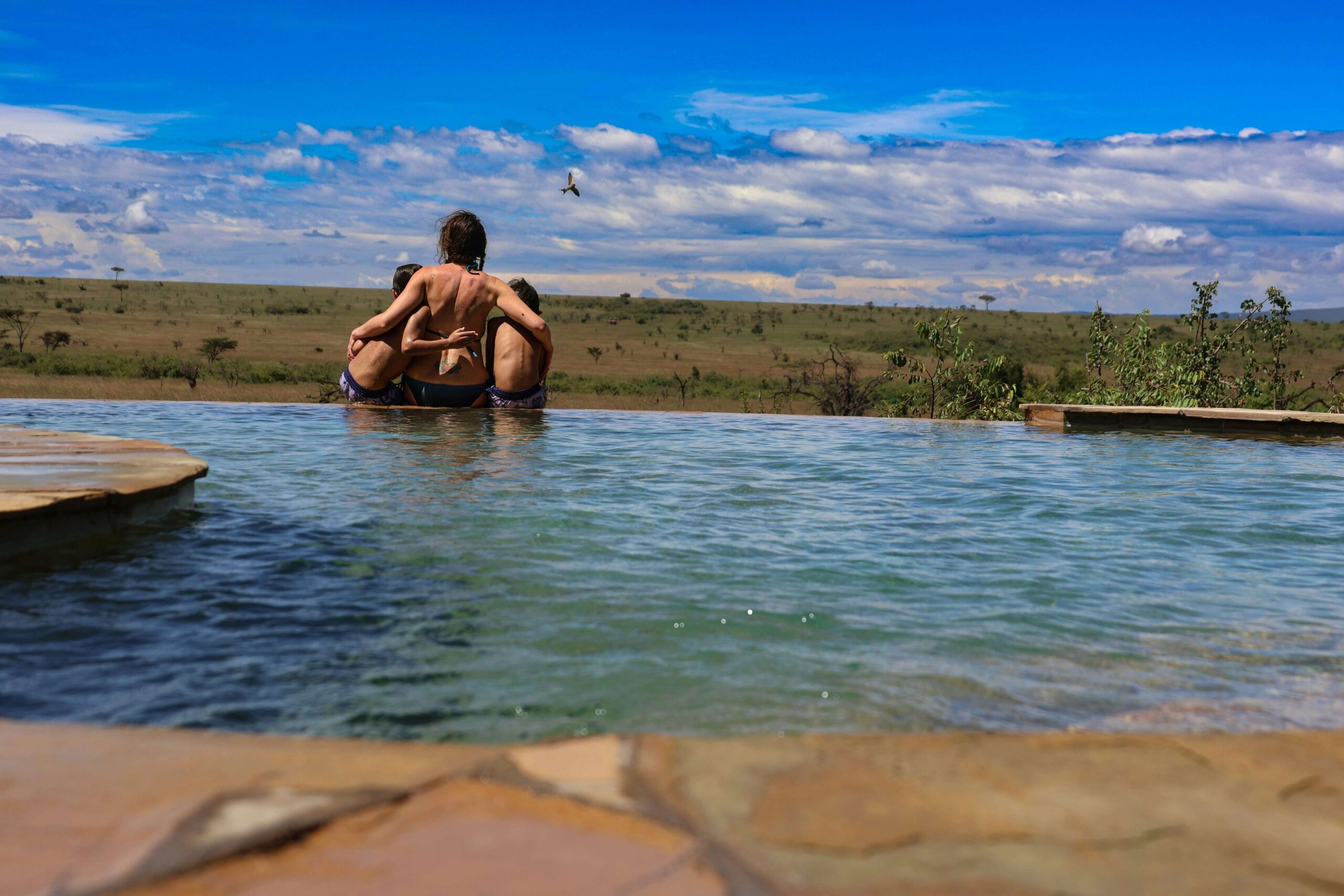 Child swimming in a safari lodge pool overlooking the Masai Mara landscape