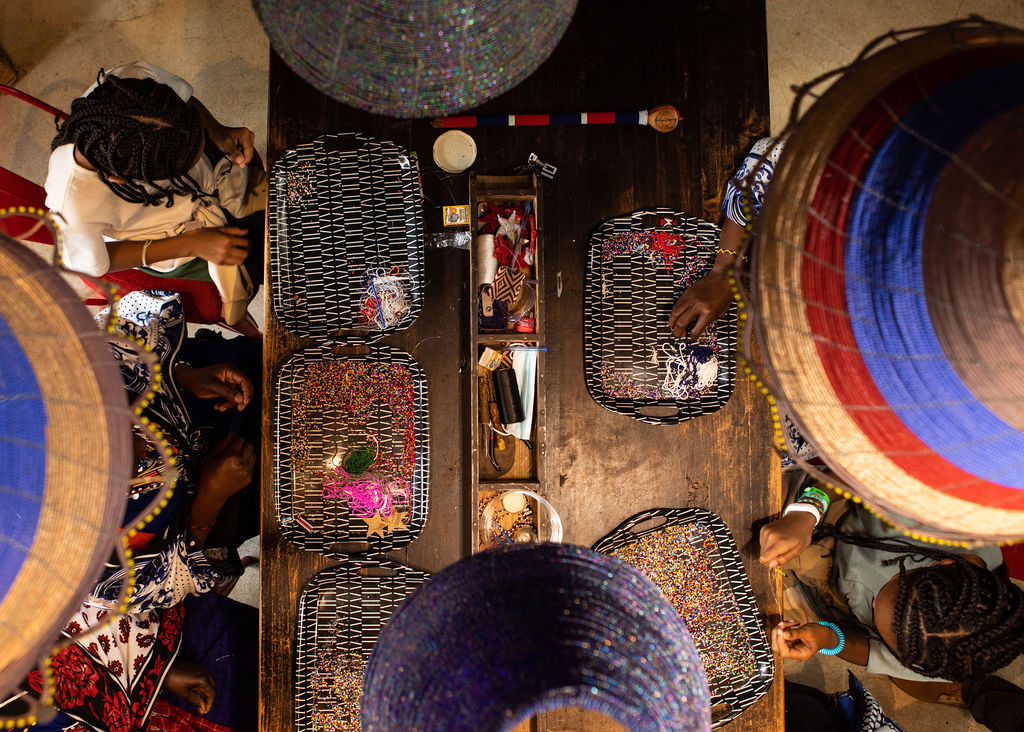 Overhead view of local Masai women, known as Bead Mamas, creating traditional beaded jewelry in a Masai Mara safari camp as part of a sustainable tourism initiative
