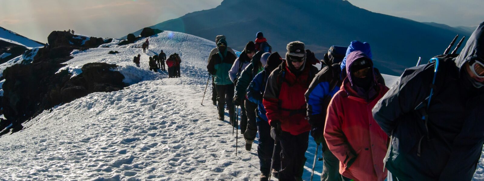Final ascent to the top of Kilimanjaro or Uhuru Peak. A line of hikers stepping over snow