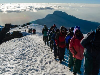 crispin-jones-OjRZ6WTghsY-unsplash Final ascent to the top of Kilimanjaro or Uhuru Peak. A line of hikers stepping over snow