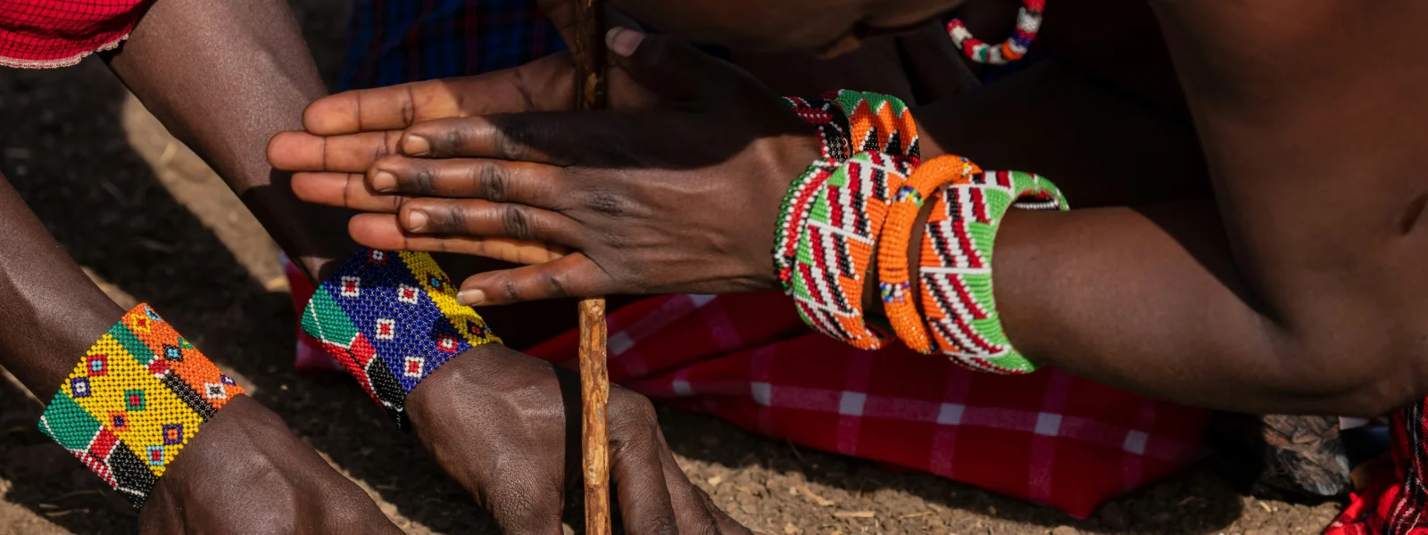 the maasai lighting a fire with sticks on a maasai village visit in masai mara